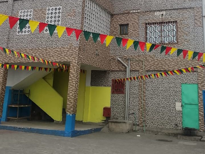 Cour du Site II : bâtiment en carreaux, escalier jaune et fanions